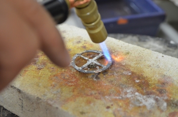 Soldering the bezel on; the silver dish underneath